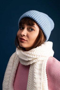 Güzel genç bir kadın neşeli poz veriyor, rahat bir sonbahar modası içinde, mavi bir arka plana karşı..