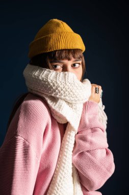 Pembe kazak ve şapka giymiş genç ve güzel bir kadın eğlenceli bir an için neşeli bir poz veriyor..