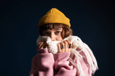 Genç bir kadın şık, sıcak elbisesiyle poz veriyor, sonbahar sezonunu coşkuyla kucaklıyor..