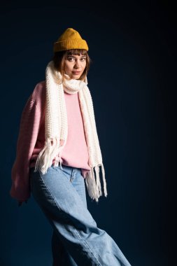 Güzel, genç bir kadın, koyu bir arkaplanda şık bir şekilde poz veriyor..