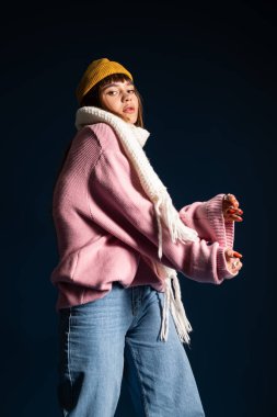 Güzel ve genç bir kadın, sıcak kıyafetler içinde, kendine güvenerek, kış mevsiminin ruhunu kutluyor..