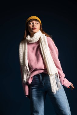 Genç bir kadın sıcak kıyafetlerini sergiliyor, sonbaharın somutlaştırıcı cazibesini özgüvenle sunuyor..