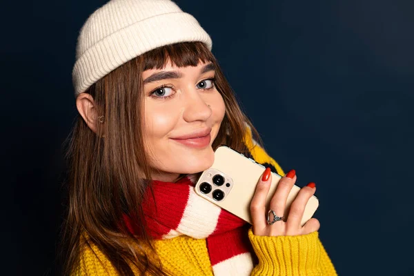 Genç bir kadın, kışın neşesini kucaklayan, parlak bir gülümseme ile kalın giysiler modelliyor..