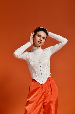 A young model in striking attire poses confidently in a vibrant setting.