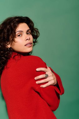 Fashionable young woman poses stylishly, showcasing a red outfit and captivating expression.