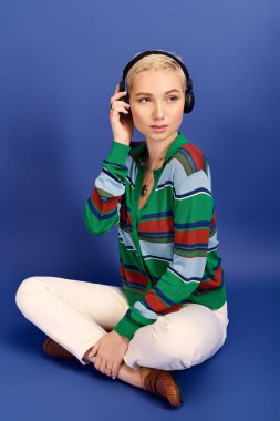 Genç ve güzel bir kadın, modaya uygun giyinmiş, kendine güvenen bir şekilde müzik dinliyor..