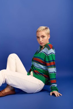 Şık, genç bir kadın kendine güvenerek oturur ve şık kıyafetlerini sergiler..