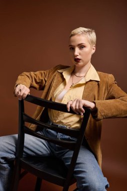 Moda kıyafetli genç bir kadın kendine güvenerek oturmuş moda anlayışını sergiliyor..