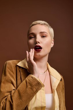 Şık genç kadın zarif bir şekilde poz veriyor, şık kıyafetiyle ve kendine güvenen makyajıyla hava atıyor..