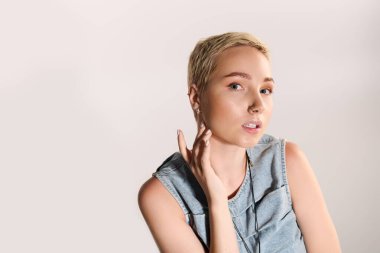 Çekici genç kadın kendine güvenerek poz veriyor, modaya uygun giyinmiş ve tarzını ifade ediyor..