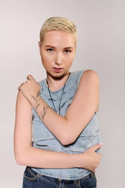 Genç, modaya uygun bir kadın, modaya uygun bir kot bluzu ve çarpıcı dövmeleri ile benzersiz tarzını sergiliyor..