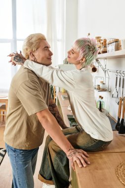 Sevgili eşler sıcak, güneşli mutfaklarında birlikte yemek pişirirken tatlı bir kucaklaşmayı paylaşırlar..