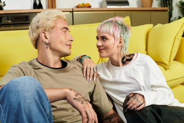 Genç çift sıcak bir gülümsemeyi paylaşırken aynı zamanda güzel bir oturma odasında eğleniyorlar..