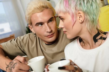 İki genç aşık, parlak bir odada sıcak kahve içerken birbirlerinin gözlerinin içine bakarlar..