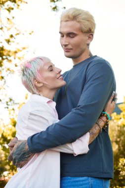 Parkta, sevgi dolu bir çift kucaklaşır. Gülüşleri derin bağlantılarını gösterir..