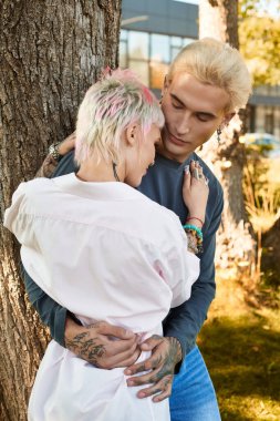 Sevgi dolu bir çift, uzun bir ağacın altında şefkatle kucaklaşır ve keyifli bir öğleden sonranın tadını çıkarırlar..