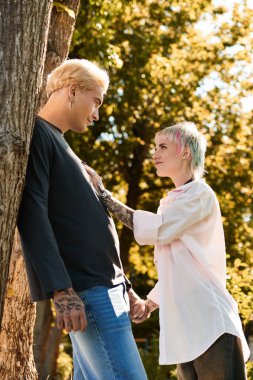 Sevgi dolu çift, altın yaprakların altında derin bir bağ kurar. Elleri birbirine dolanır. Yumuşak güneş ışığında parlar..