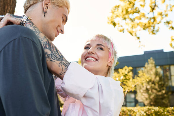 A loving couple embraces with smiles, enjoying a beautiful day in the parks greenery.