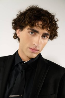 Bu genç adam şık bir siyah giysi ve kendine güvenen bir tavırla tarzını sergiliyor..