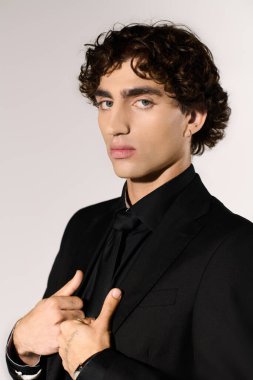 Genç, şık bir adam modaya uygun bir stüdyo ortamında kendine güven ve cazibe yayıyor..