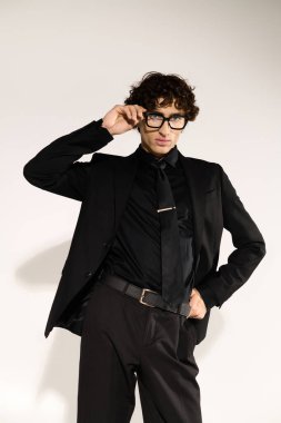 Yakışıklı genç adam gözlüğünü düzeltirken tarz yayıyor, şık giyiniyor..