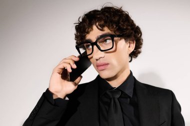 Kendine güveni tam yakışıklı bir adam. Önden giyinmiş. Bir telefon görüşmesi yapıyor.