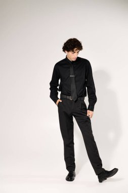 Tarz sahibi genç bir adam, kendine güvenerek, modern modanın somutlaştırıcı, gösterişli siyah bir elbise içinde poz verir..