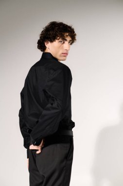 Şık giyinmiş, kendine güvenen genç bir adam temiz bir arka plana karşı poz veriyor..