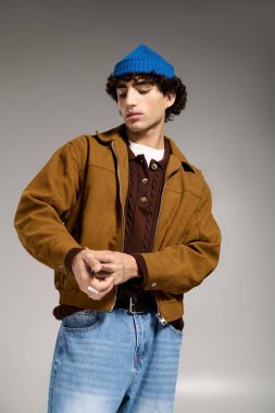 Kendine güvenen genç adam kıyafetlerini ayarlar, günlük ve şık unsurları kolayca harmanlar..