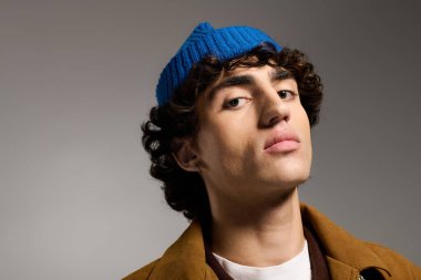 Yakışıklı genç adam kendine güvenerek poz veriyor. Eşsiz mavi bir bere ve şık bir iç giyim tarzıyla..