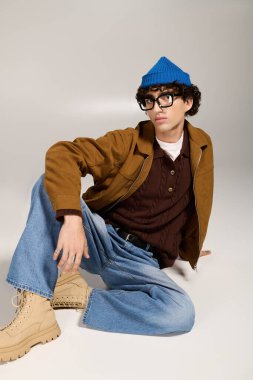 Genç ve yakışıklı bir beyefendi, modaya uygun giyinmiş, neşeli bir bereyle poz veriyor..