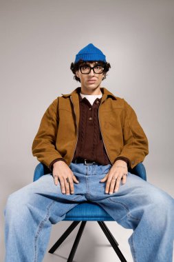 Modayı takip eden genç adam şık bir sandalyeye oturmuş, kendine has modasıyla hava atıyor..