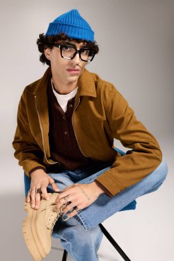 Genç, yakışıklı bir adam modaya uygun bir şekilde poz veriyor. Benzersiz moda anlayışının altını çiziyor..