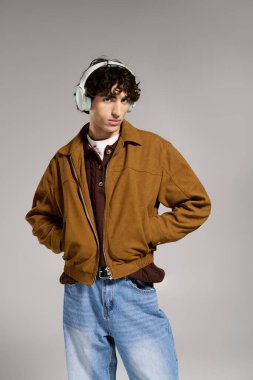 Şık giyinmiş yakışıklı genç adam kulaklık takarken rahatça poz veriyor..