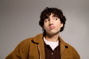 Yakışıklı genç adam modaya uygun şekilde poz veriyor, benzersiz stilini ve karizmasını vurguluyor..