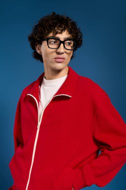 Yakışıklı genç adam canlı kırmızı ceketi ve modaya uygun gözlükleriyle modern modayı sergiliyor..