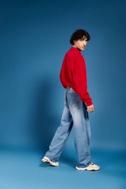 Genç, yakışıklı bir adam kendine güvenerek şık bir şekilde poz veriyor, çağdaş moda eğilimlerini vurguluyor..