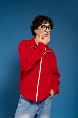Yakışıklı bir genç adam şık kırmızı bir ceket içinde özgüven ve tarz yayarak düşünceli bir şekilde poz verir..