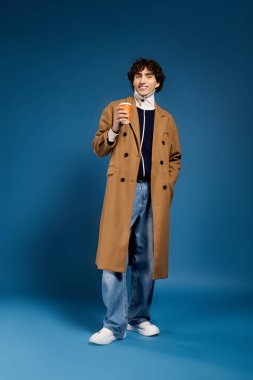 Şık giyinmiş kendine güvenen genç adam elinde fincanla modern stili parlak renklerle sergiliyor..