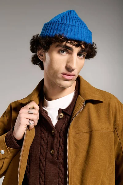 Rahat kıyafetli, genç, yakışıklı bir adam kendine güvenen mavi beresiyle poz veriyor..
