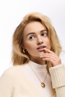 Güzel, genç, sarışın bir kadın şık bir örgü elbiseyle kış makyajı yapıyor..