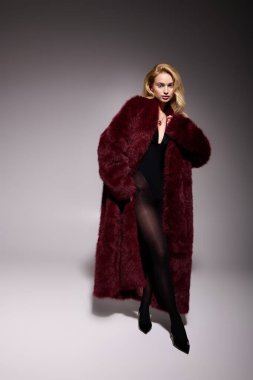 Sarışın genç bir kadın kış mevsiminde şık kırmızı bir kürk manken, zarafet saçıyor..