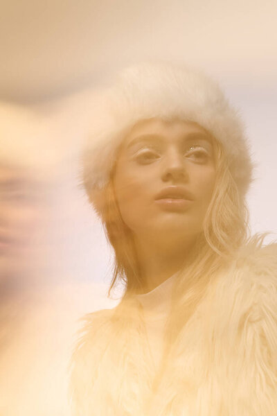 Молодая блондинка демонстрирует зимнюю элегантность с уютной одеждой и стильным макияжем.