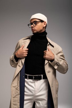 Şık giyinen kendine güvenen genç adam minimalist bir yerde yaratıcı bir poz veriyor.