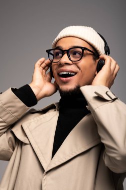 Gözlük ve kulaklık takan yakışıklı genç adam müzik dinliyor, neşe ve güven saçıyor..