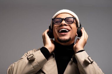 Şık bir genç adam müzik dinlerken büyük bir gülümseme sergiliyor, neşe saçıyor..