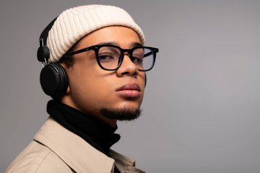 Şık bir şapka ve gözlük takan genç bir adam eşsiz tarzını ve özgüvenini sergiliyor..