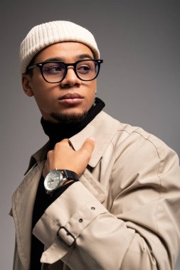 Tarafsız ortamda şık giyinmiş yakışıklı genç bir adam şık bir görünüm sergiliyor..