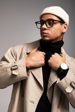 Yakışıklı genç adam yaratıcı bir stüdyo atmosferinde özgüvenle şık giysiler sergiliyor..