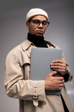 Moda tarzını ve moda anlayışını sergileyen şık giyinmiş yakışıklı genç adam içeride poz veriyor..